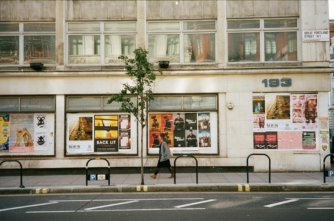 A person walking past a building with posters on it