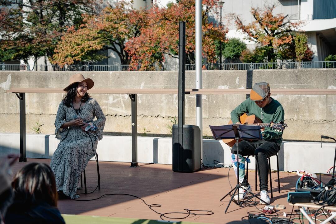 A woman sings while a man plays guitar outdoors
