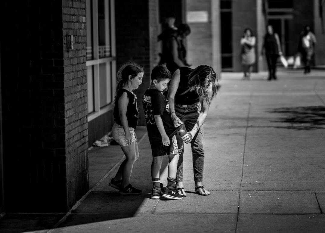 Grayscale photography of woman helping boy