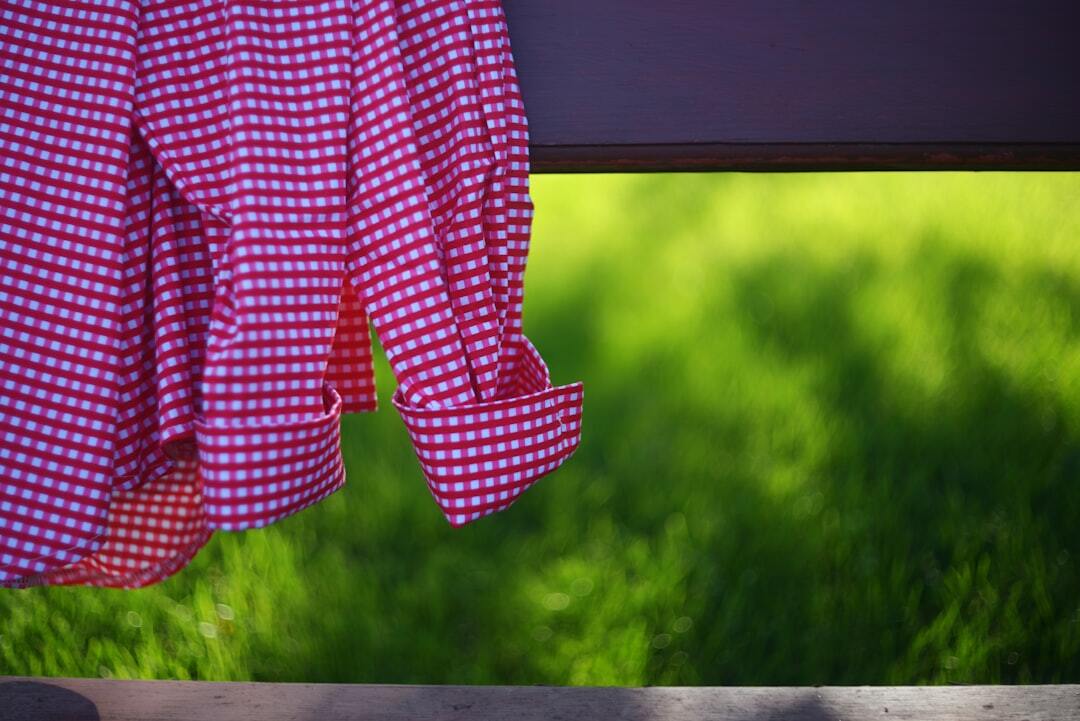Red gingham shirt sleeve against a blurred green grass background
