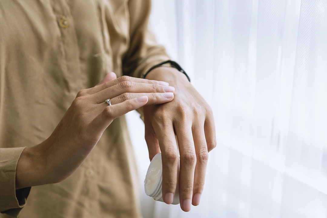 Woman applying moisturising cream to her hand during cooler weather
