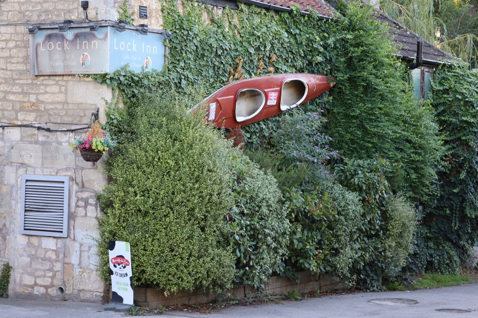 Charming Lock Inn pub with a vintage canoe framed by lush greenery in the UK. Perfect blend of nature and architecture