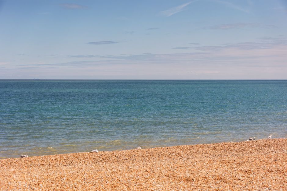 Peaceful pebble beach with clear blue sea under a bright sky in the UK